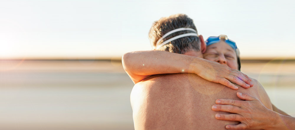 Back view of older couple hugging on beach